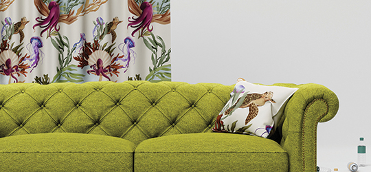Traditional green couch in front of a patterned curtain.