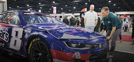 a man places a wrap on a car inside of a convention center
