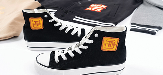 pair of black high top shoes with a heat pressed logo