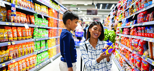 a woman and a little boy shop in a grocery store with lots of options