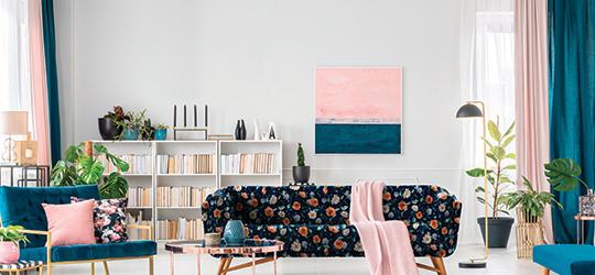 A decorated room with pink and blue colors and printed couch.